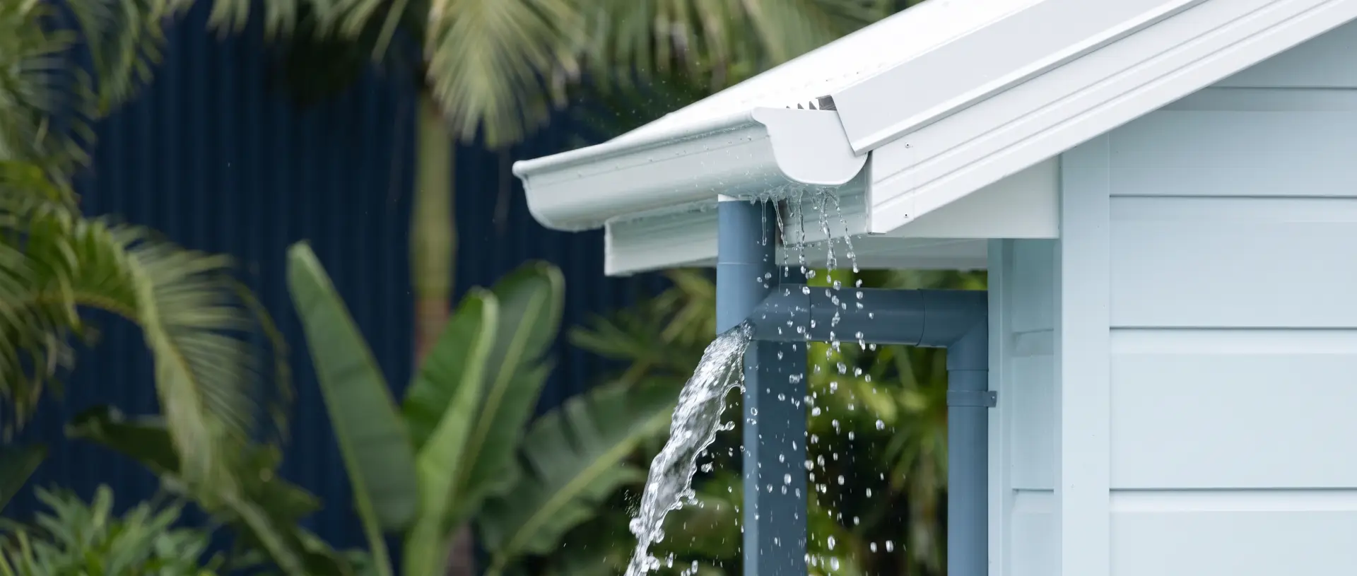 Pluie tropicale qui s’écoule d’une gouttière vers une descente d’eau.