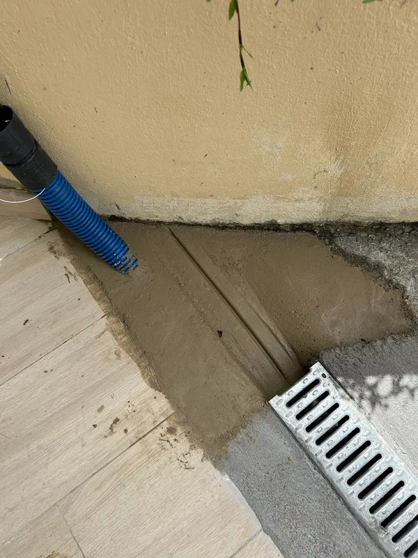 Un caniveau à grille posé au pied du mur pour recueillir l’eau de pluie.