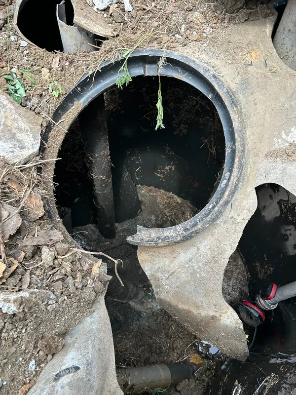 L’intérieur d’une ancienne fosse en béton, cassée et encrassée.