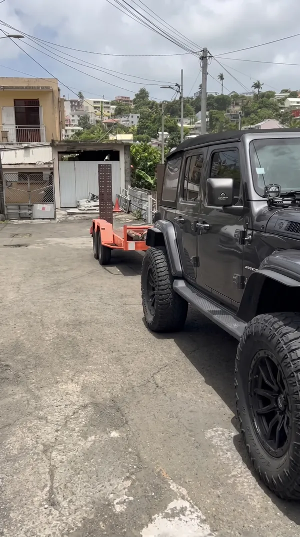 Véhicule tout-terrain tractant une remorque porte-engin pour accès difficile.