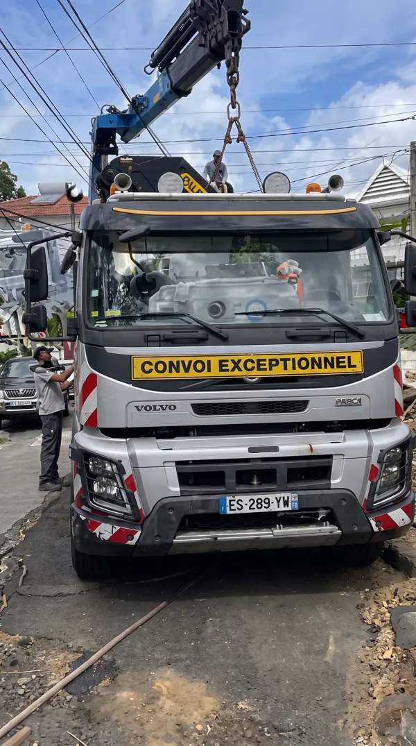 Camion-grue de chantier pour la livraison d'une micro-station d'épuration en béton.