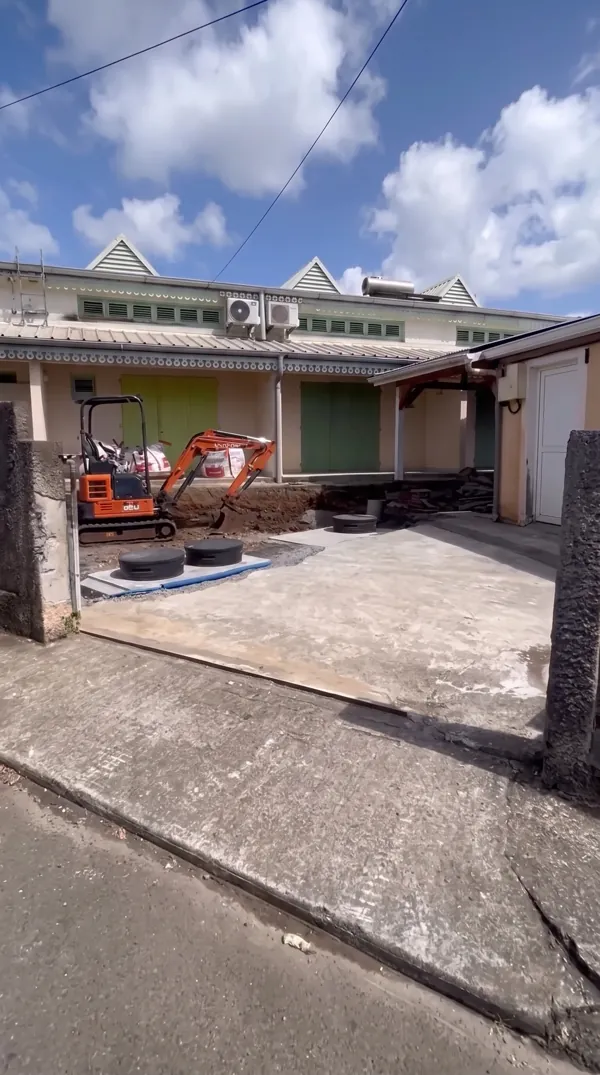 Chantier d'aménagement d'un parking au-dessus d'une micro-station d'assainissement avec mini-pelle.