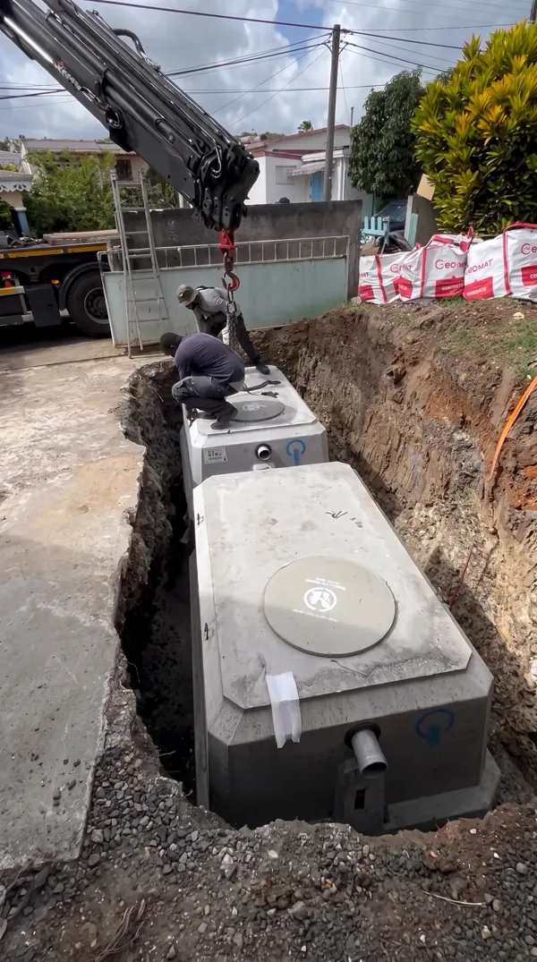 Pose de cuves d'assainissement en béton dans une tranchée.