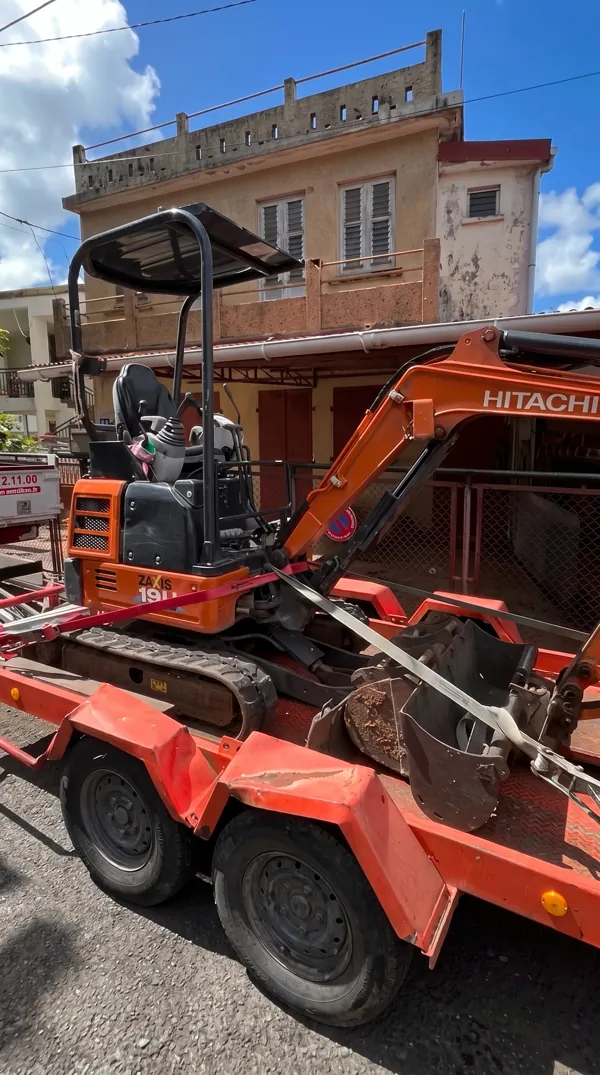 Mini-pelle Hitachi orange sur une remorque après la fin des travaux.
