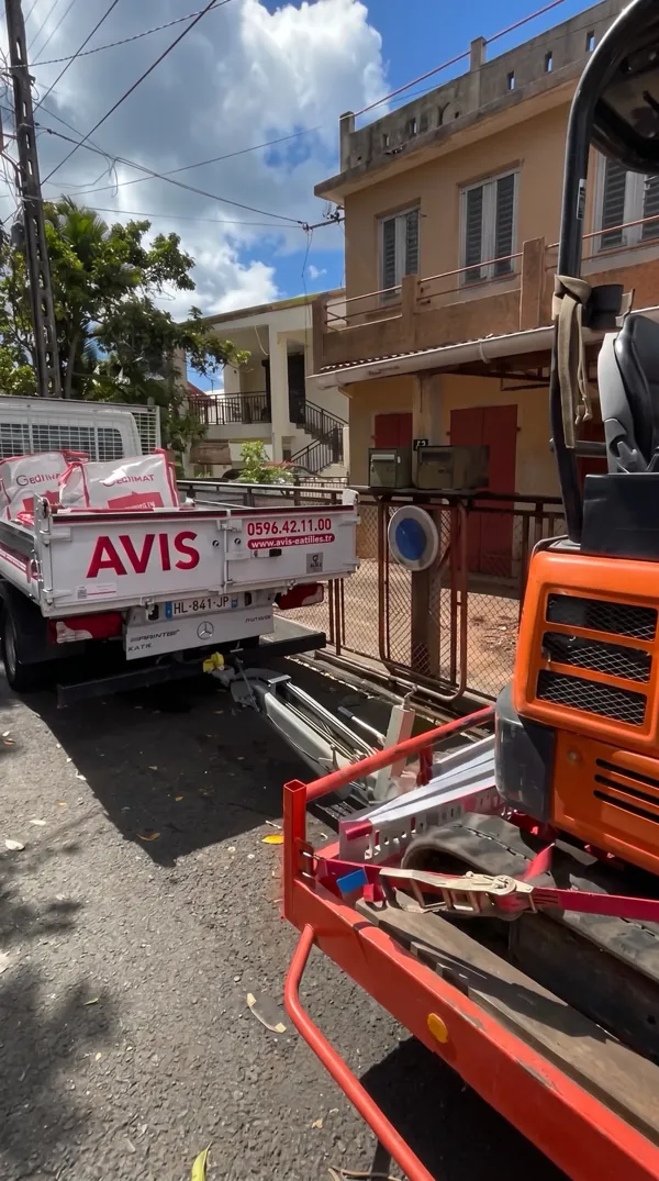 Camionnette et mini-pelle sur remorque prêtes pour l'évacuation après un chantier.