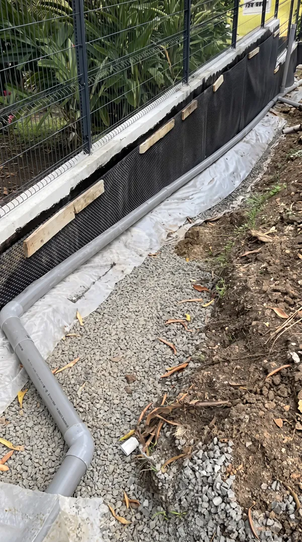 Pose d'un drain et de canalisations d'eaux pluviales le long d'un mur.