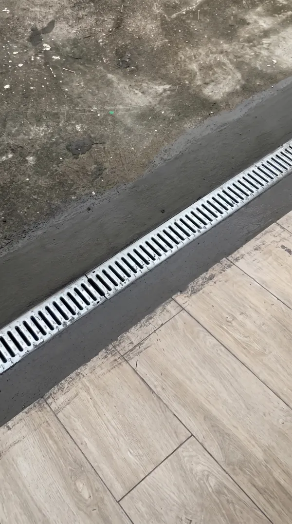 Pose d'un caniveau de drainage des eaux pluviales le long d'une terrasse.