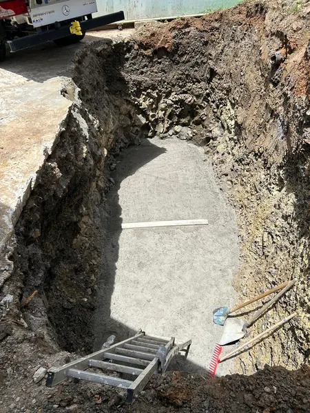 Le fond de la fouille recouvert d’une dalle de béton, l’échelle appuyée contre la paroi.