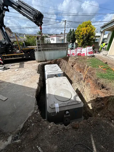 La cuve en béton suspendue à la grue du camion, au-dessus de la fouille.