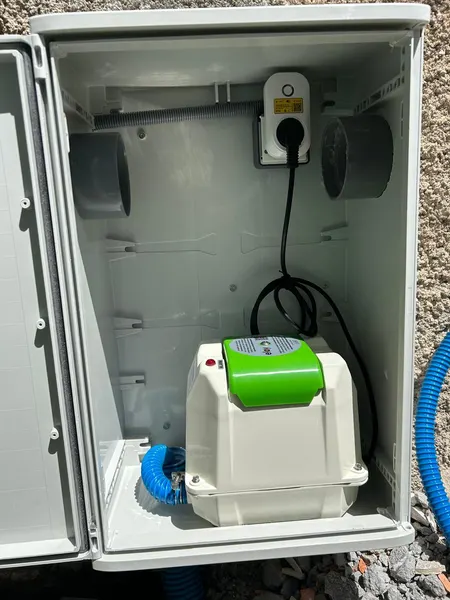 Un coffret ouvert avec le surpresseur d’air de la micro-station et ses tuyaux.